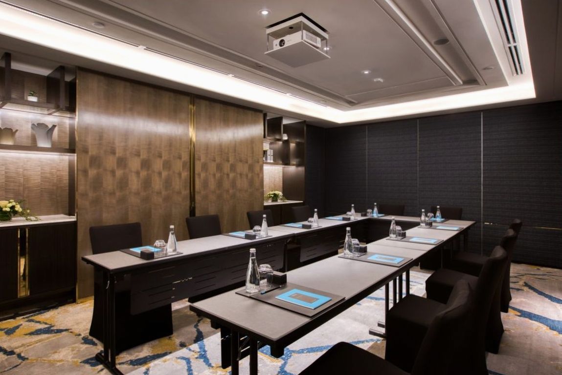 Intimate lounge setting with card table, green felt, brass pendant lamps and dark timber panelling